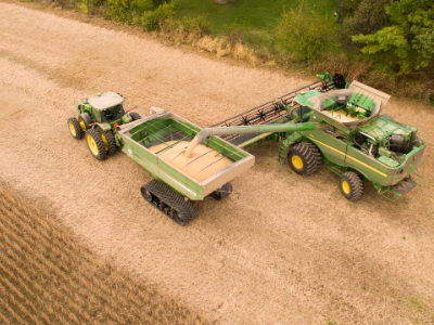 Farmers using equipment to harvest soybeans from a field